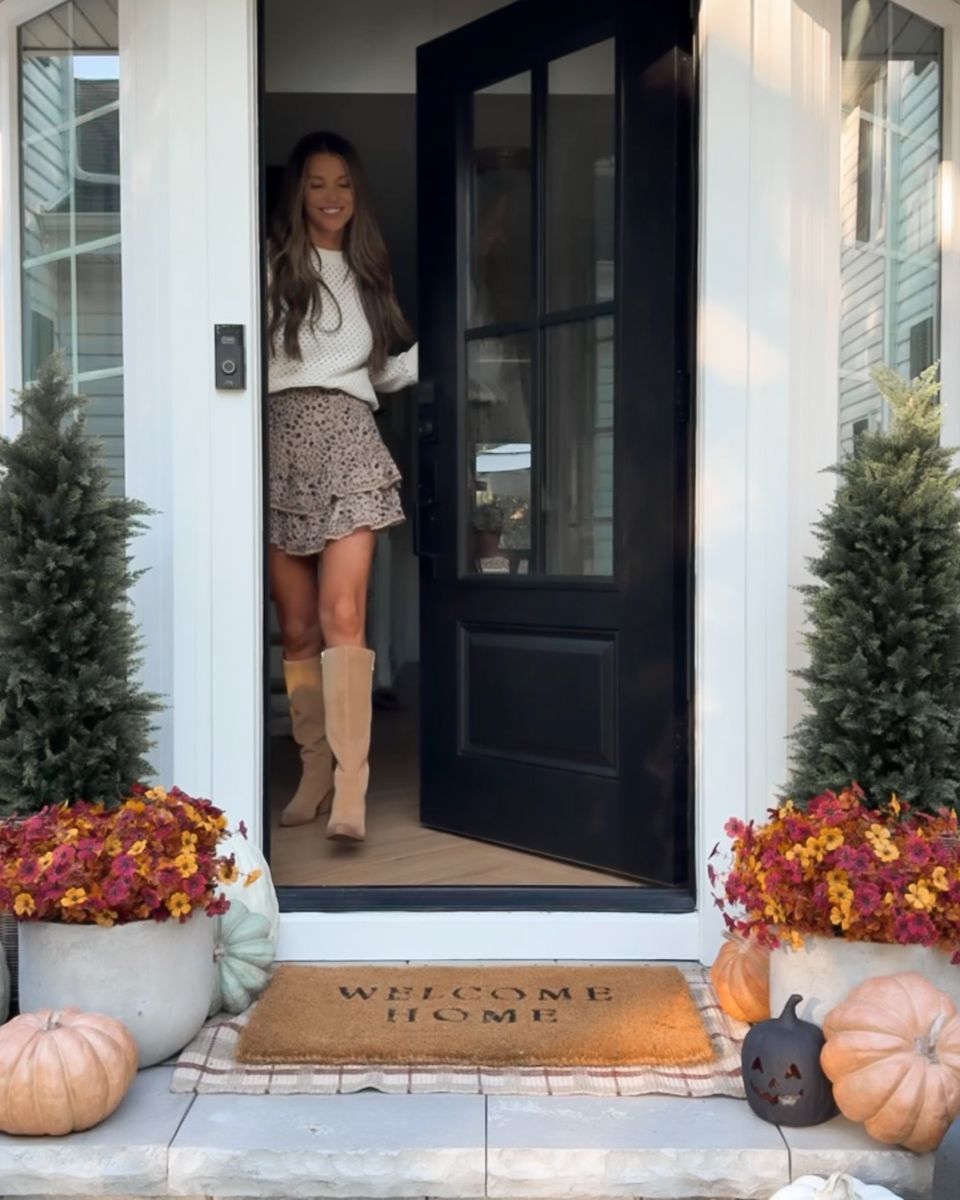 Lauren waving from the open black 4 Lite door of her white house, porch styled for fall