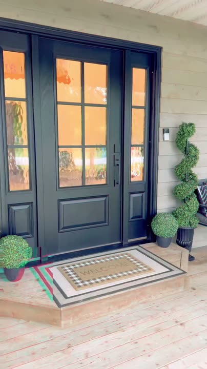 Reel by @SDOTDIY: A green front door swapped for a black six-pane door with sidelights on a wood porch.