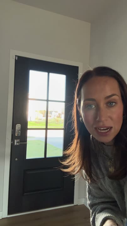 Reel by @bysophialee: Black front door with six glass panes seen from inside the entry, a woman beside it.