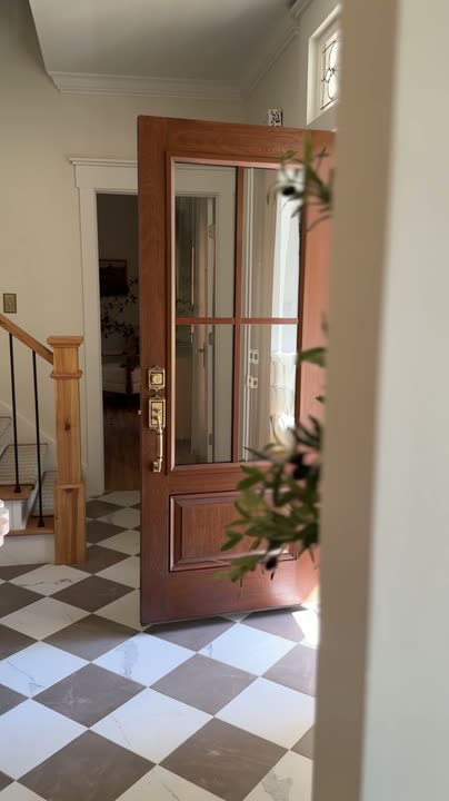 Reel by @kenziemariehome: Gunstock-stained door with four glass panes seen from inside a bright entryway, then the two-storey house with its wide porch.