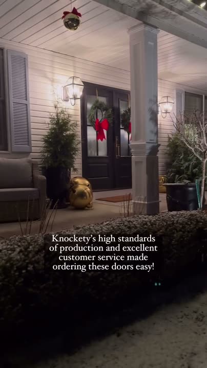 Reel by @peonyandhoney: Black double front doors with four glass panes each and red wreaths, on a lit porch at dusk.