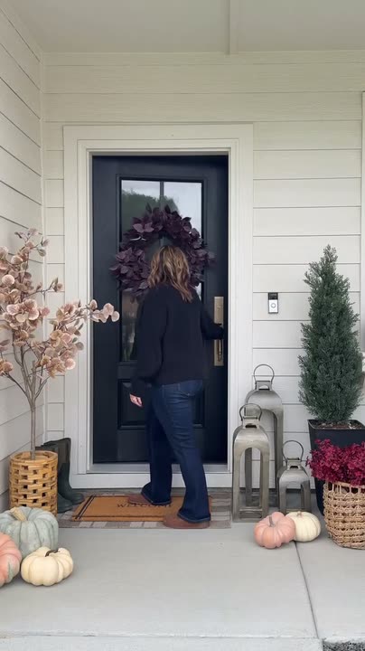 Reel by @theresachristinehome: Black front door with glass panels, a burgundy wreath and a brass handle; pumpkins and lanterns on the porch.